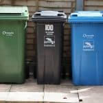 three bins out on pavement, one numbered with stickers