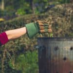 gardener placing weeds into incinerator bin