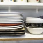 stack of non matching bowls and plates in kitchen cabinet