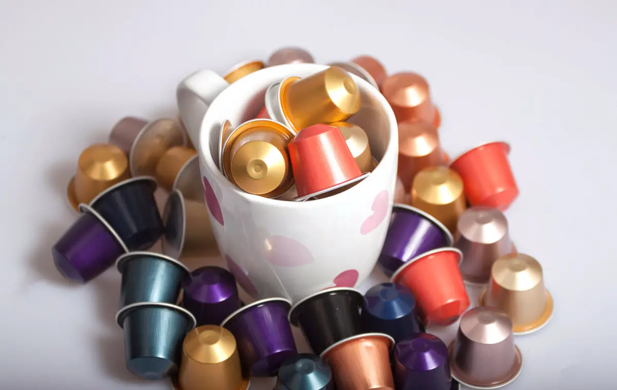 coffee capsules scattered in and around mug